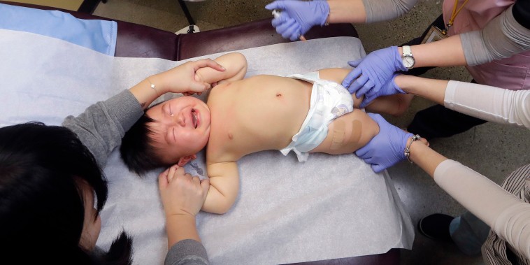 Image: One-year-old Abel Zhang cries as he receives the last of three inoculations, including a vaccine for measles, mumps, and rubella (MMR), at the International Community Health Services