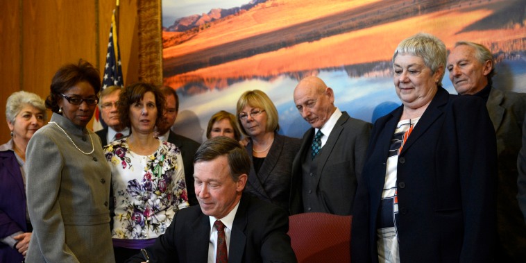 Image: Colorado Governor John Hickenlooper signs a gun control bill at the state capitol in Denver on March 20, 2013.