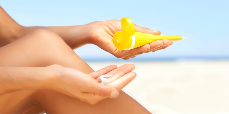 Image: Woman applying sun cream to legs