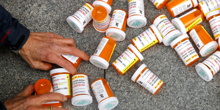 A protester gathers containers depicting OxyContin prescription pill bottles after a demonstration against the FDA's opioid prescription drug approval practices on April 5, 2019, in front of the Department of Health and Human Services' headquarters in Washington.