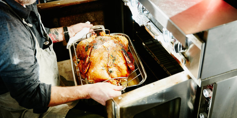 Man pulling cooked turkey out of oven