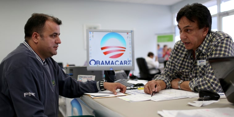 Image: Ariel Fernandez, left, sits with Noel Nogues, an insurance adviser, as he signs up for the Affordable Care Act in Florida in 2015.