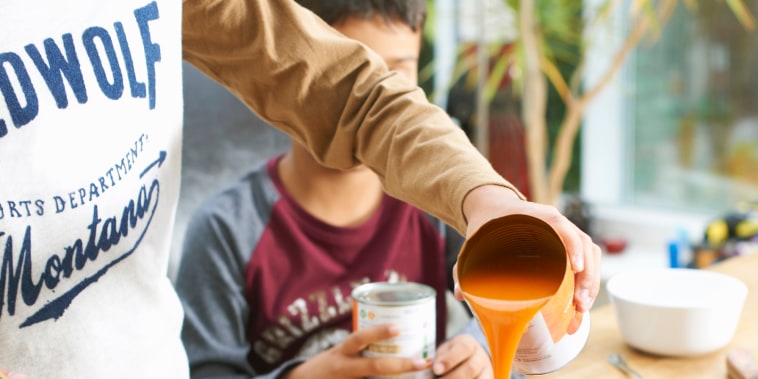 Cropped shot of boy pouring tin of tomato soup into saucepan