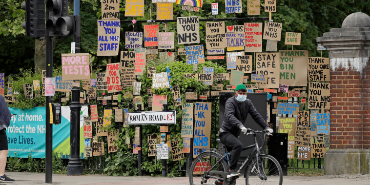 A cyclist passes signs supporting the National Health Service in a display coordinated by artist and local resident Peter Liversidge in east London, on April 27, 2020.