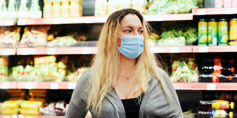 Woman buying food in grocery store, wearing medical mask
