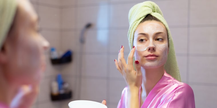 Woman putting facial mask in the bathroom