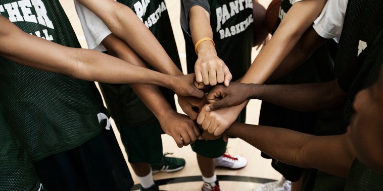 Basketball team putting fists together in huddle
