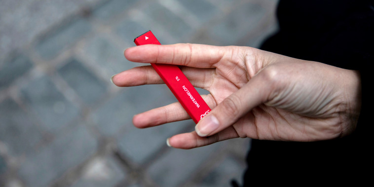 A woman holds a Puff Bar flavored disposable vape device in New York on Jan. 31, 2020.