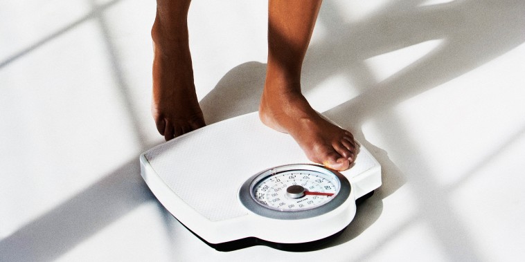 Woman standing on weighing scales, low section