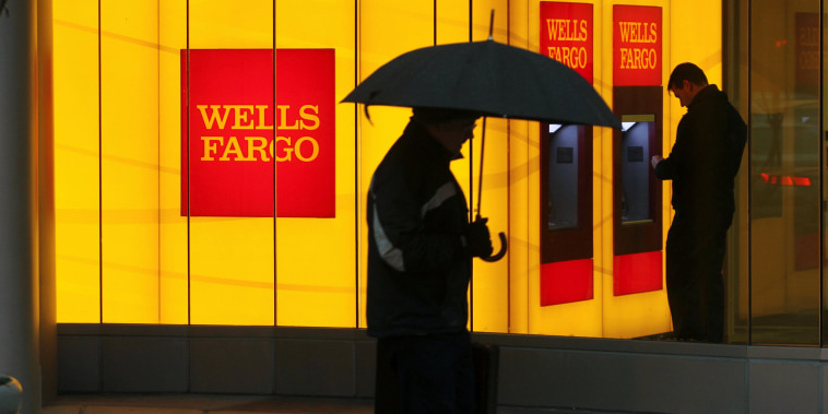 Image: A man walks past a Wells Fargo Bank branch on a rainy morning in Washington