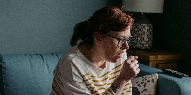 Woman Coughing While Sitting On Sofa At Home