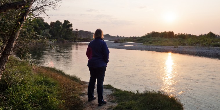 Overweight Woman Standing on a Riverbank at Sunrise