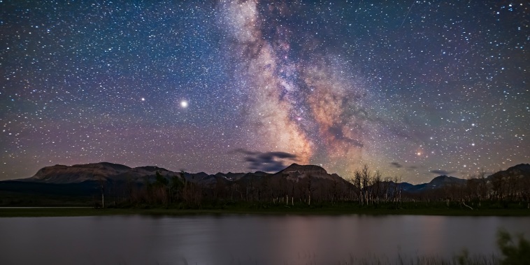 The galactic core area of the Milky Way over Maskinonge Pond in Waterton Lakes National Park, Alberta. Jupiter is the bright object at left, with Saturn dimmer to the left (east) of Jupiter. In the summer of 2020 the two planets were close together in the