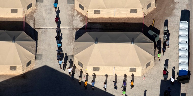 Image: Immigrant children are led by staff in single file between tents at a detention facility in Tornillo, Texas