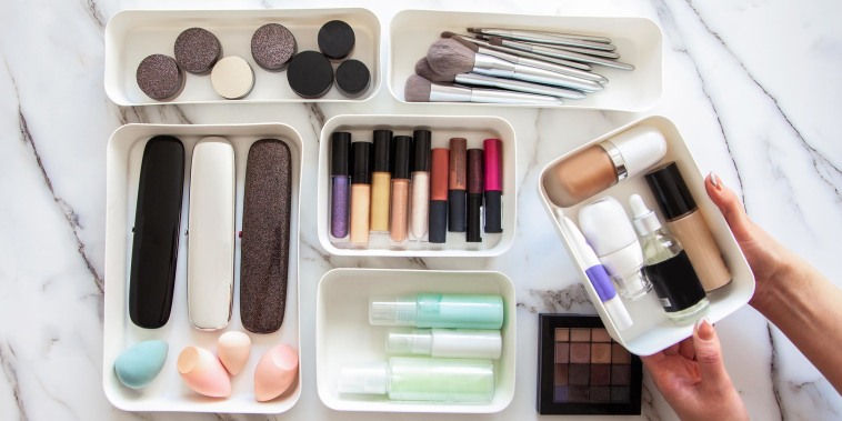 Overhead image of a Woman organizing her makeup, brushes and beauty items, in white storage containers