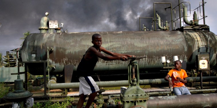 Image: Children play on an abandoned oil flow station near smoke from a burning oil pipe in Kegbara Dere, Nigeria, in 2007.