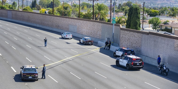 Image: Yellow crime scene tape stretches across the northbound lanes of the 55 freeway as police investigators walk the freeway looking for evidence following a shooting on May 21, 2021 in Orange, Calif.