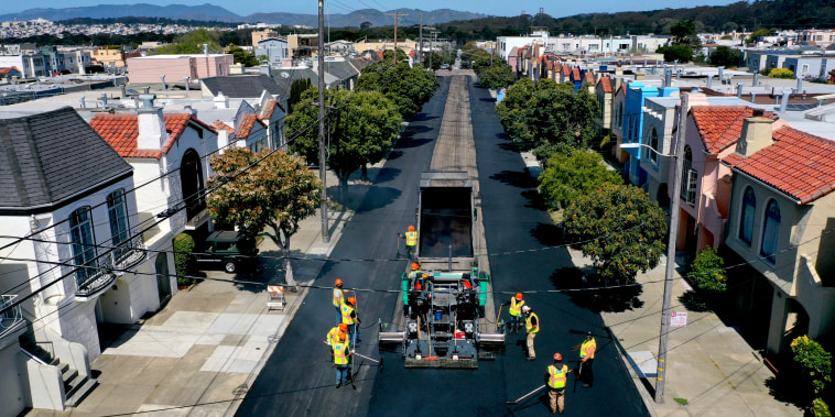 Workers with the San Francisco Department of Public Works repave a section of 24th Avenue on April 8, 2021 in San Francisco.