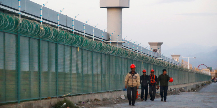 Image: Workers walk by the perimeter fence of what is officially known as a vocational skills education centre in Dabancheng in Xinjiang Uighur Autonomous Region, China.