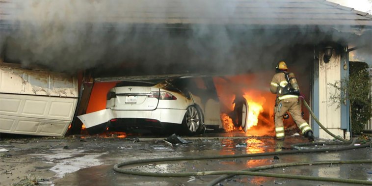 The Orange County Fire Authority battles a fire from a burning Tesla inside a garage in Orange County, Calif., in 2017.  When firefighters removed the SUV from the garage to assess the fire, they identified the fuel source as the SUV's high-voltage battery pack.