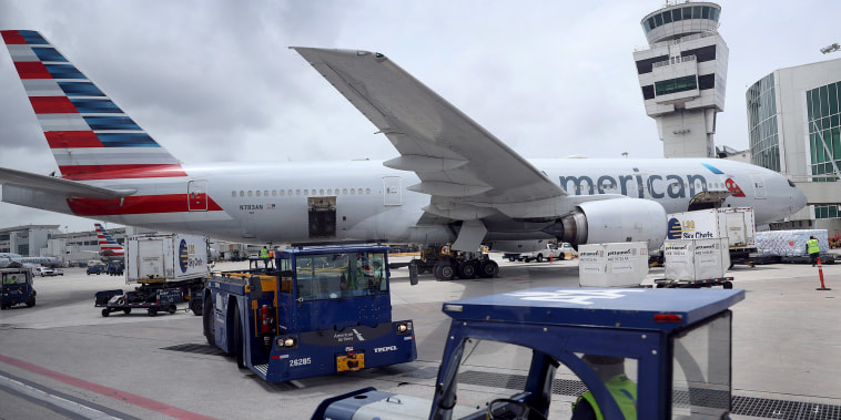 Image: Workers prepare an American Airlines plane at a gate before its flight from the Miami International Airport