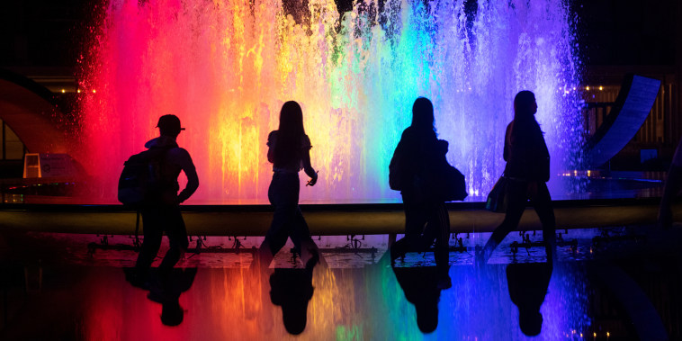 People walk past the fountain at Lincoln Center for the Performing Arts lit up in Pride colors on June 2, 2021, in New York.