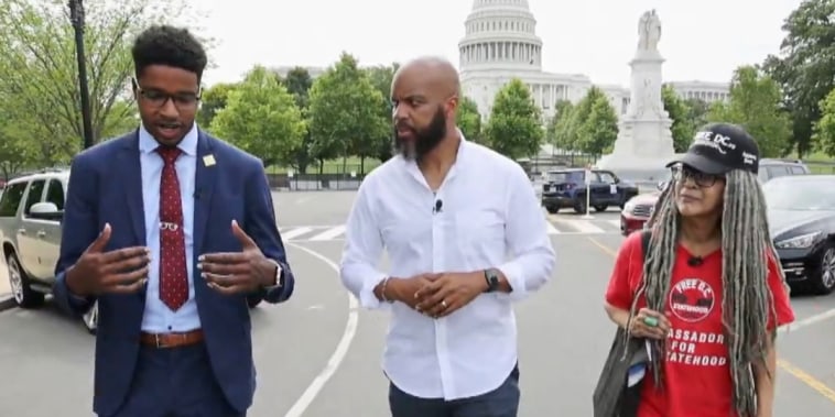 Image: Trymaine Lee, center, speaks with Jamal Holtz from \"51 for 51\" and Anise Jenkins from \"Stand Up! for Democracy in DC\".