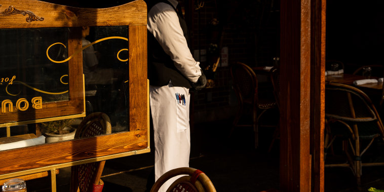 Image: A waiter at a restaurant on April 28, 2021 in New York City where restaurants are struggling with a labor shortage that threatens to hobble the industry's comeback just as its getting started.