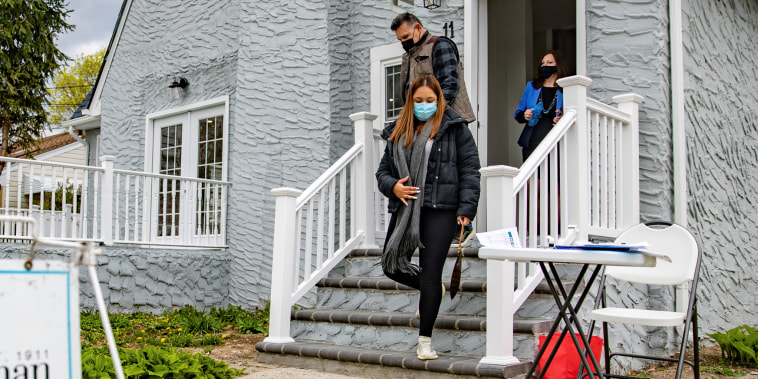 Real estate agent Rosa Arrigo stands in the doorway as Giovani and Nicole Quiroz visit an open house in West Hempstead, N.Y., on April 18, 2021.