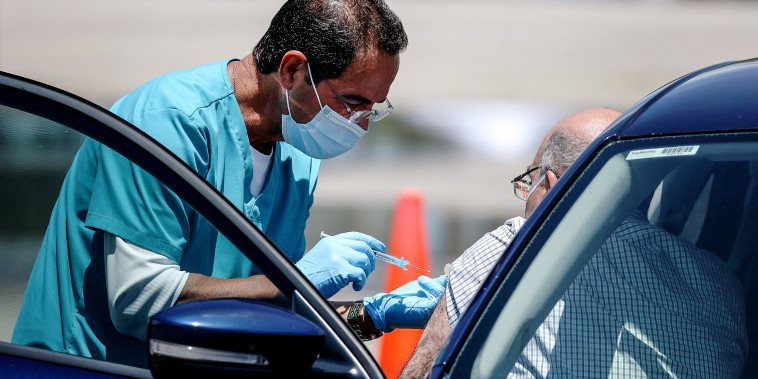A healthcare worker administers a vaccine at a drive-thru site setup by Miami-Dade and Nomi Health in Tropical Park on July 26, 2021 in Miami.