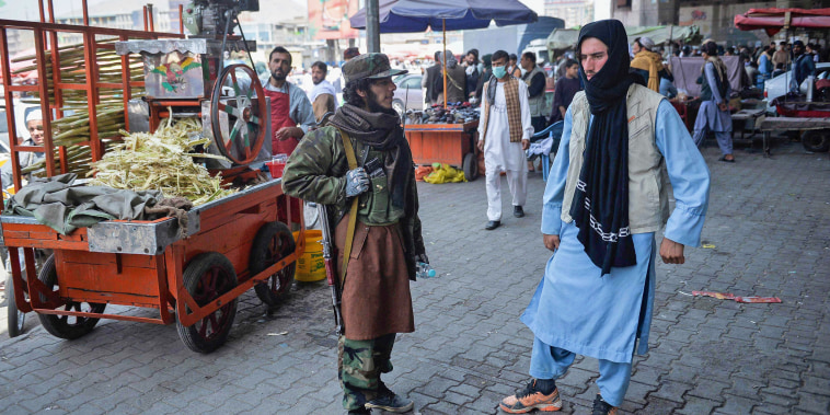 A Taliban fighter stands by a kiosk selling sugarcane juice at a market area in the Kote Sangi area of Kabul on Aug. 17, 2021.