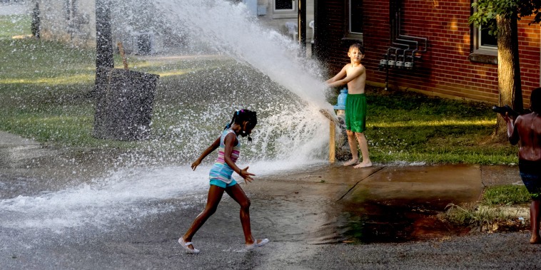 A group of children play with water from an open fire