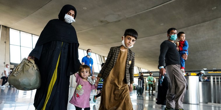 Image: Afghan refugees walk to a bus taking them to a processing center upon arrival at Dulles International Airport in Dulles, Va., on Aug. 27, 2021.