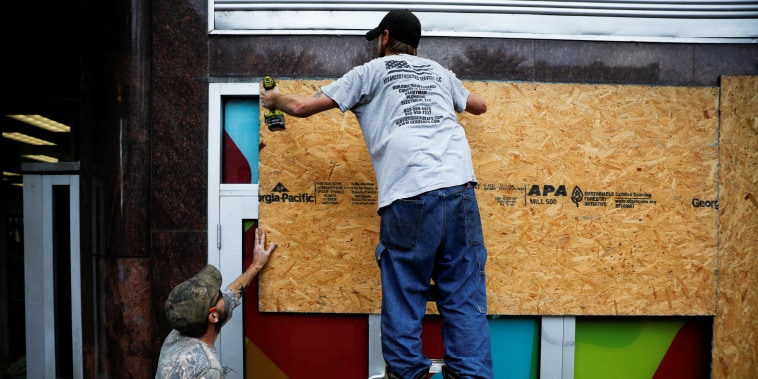 Men place plywood in front of a store in preparation for Hurricane Ida in New Orleans on Aug. 28, 2021.