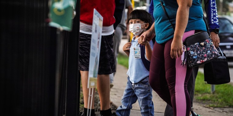 A student and his parents walk into an elementary school on the first day of school in Houston, Texas, on Aug. 23, 2021.