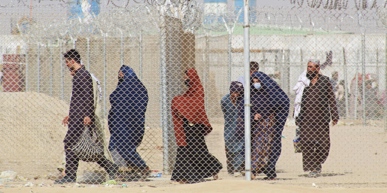 Afghan nationals walk along a fenced corridor as they enter Pakistan through the Pakistan-Afghanistan border crossing point in Chaman on Aug. 30, 2021.
