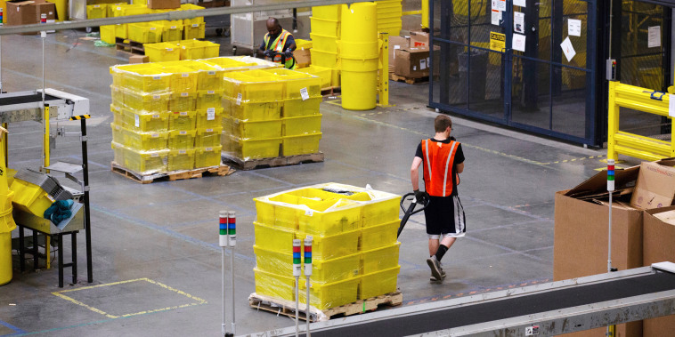 An employee pulls a pallet jack carrying plastic crates containing online orders at the Amazon fulfillment center in Robbinsville, N.J., on June 7, 2018.