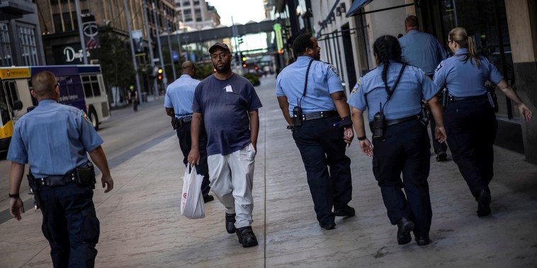 A man walks by a group of police officers in downtown Minneapolis on Sept. 8, 2021.