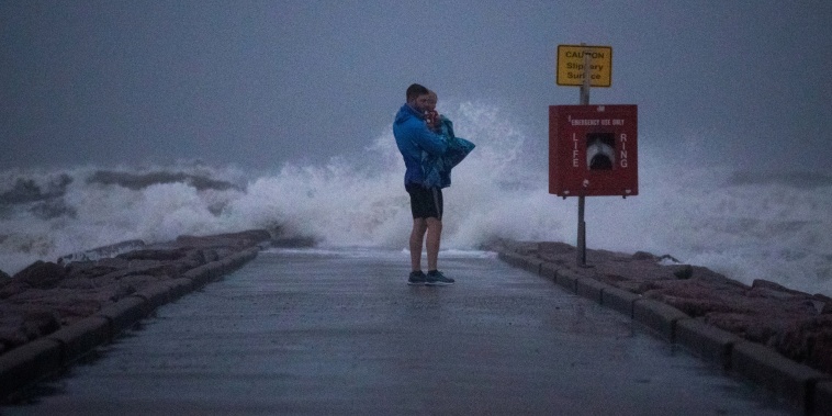 A Texas resident holds his son as he stands near breaking waves on a pier ahead of the arrival of Tropical Storm Nicholas in Galveston, Texas, on Sept. 13, 2021.