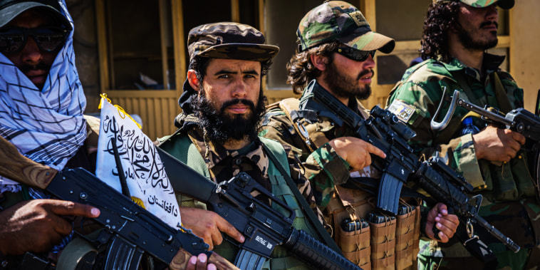 Taliban fighters line up to show off their weapons as they control access to the Abbey Gate and make Afghans with travel documents wait in Kabul, Afghanistan, on Aug. 25, 2021.