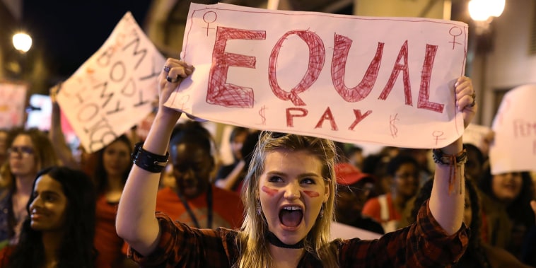 Image: A protester holds a sign that readings \"Equal Pay\"
