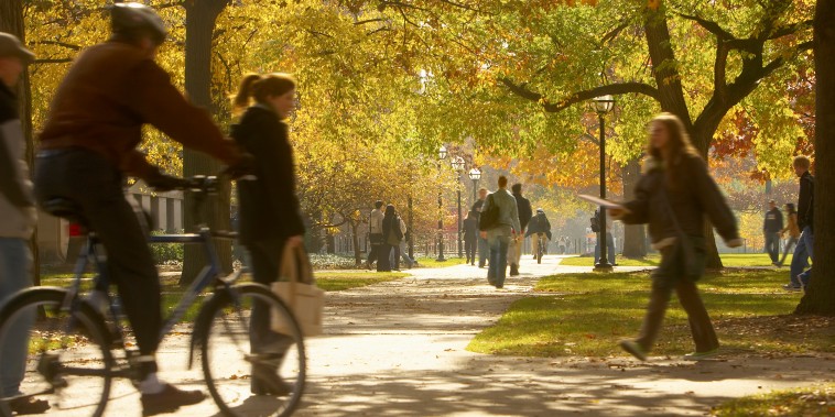 Students walking on footpaths on college campus, autumn