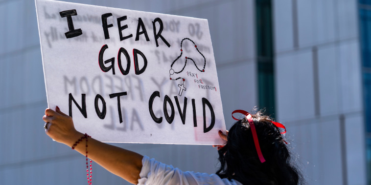 A protestor opposing Covid-19 vaccine mandates holds a sign in front of City Hall in downtown Los Angeles on Sept. 18, 2021.