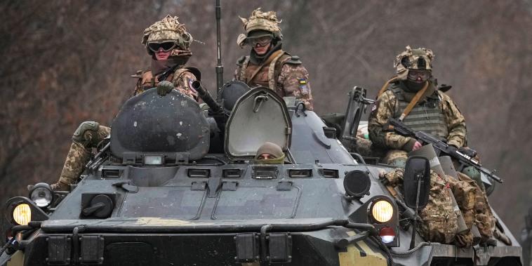 Image: Ukrainian soldiers sit atop armored personnel carriers driving on a road in the Donetsk region, eastern Ukraine on Feb. 24, 2022.