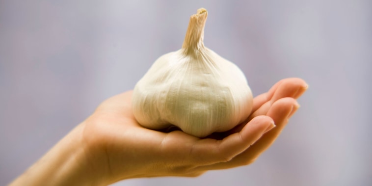 Woman holding garlic bulb, close-up