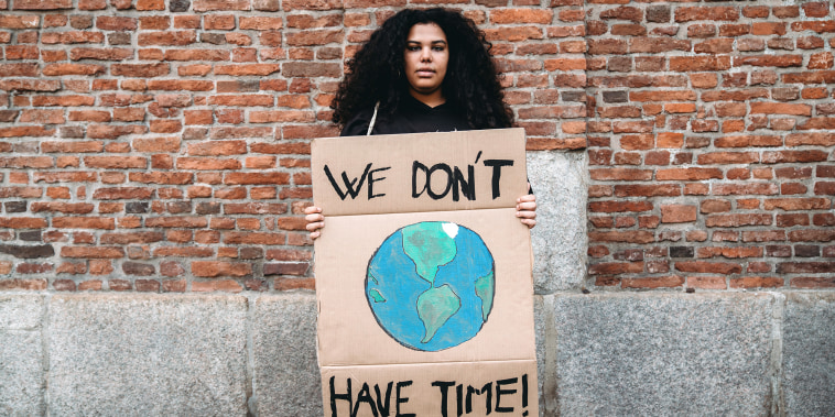 Portrait of a young adult woman holding a cardboard sign against climate change