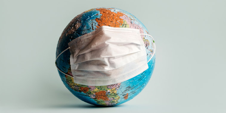 Globe made of jigsaw puzzles with a protective medical mask