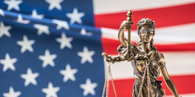 Statue of Lady Justice in front of American flag