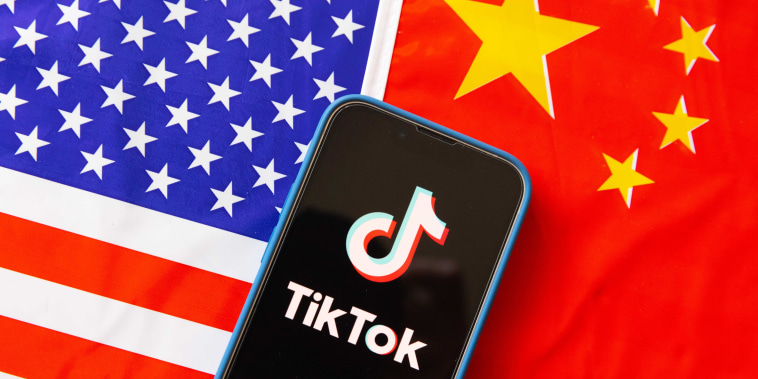 The TikTok logo on a phone in front of U.S. and Chinese flags.