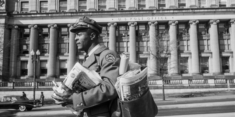 A postal worker carries a bag full of mail in Washington DC, April 1957.